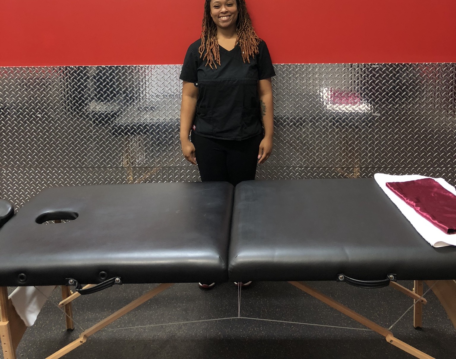 Danielle, Licensed Massage Therapist, beside a treatment table